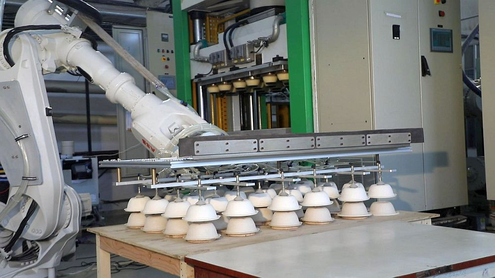 Factory robotic arm moving molded paper products